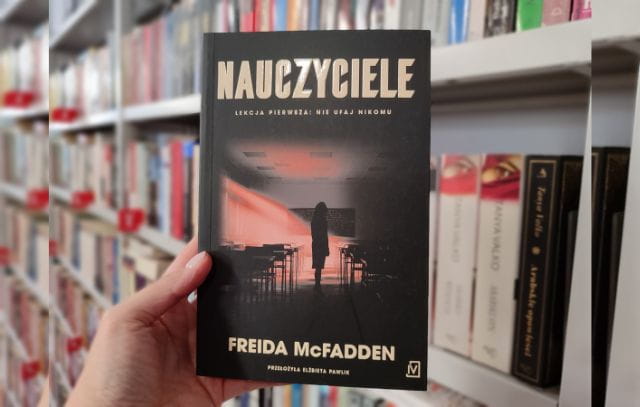 Zdjęcie książki Nauczyciele F. McFadden na tle regałów z książkami.
