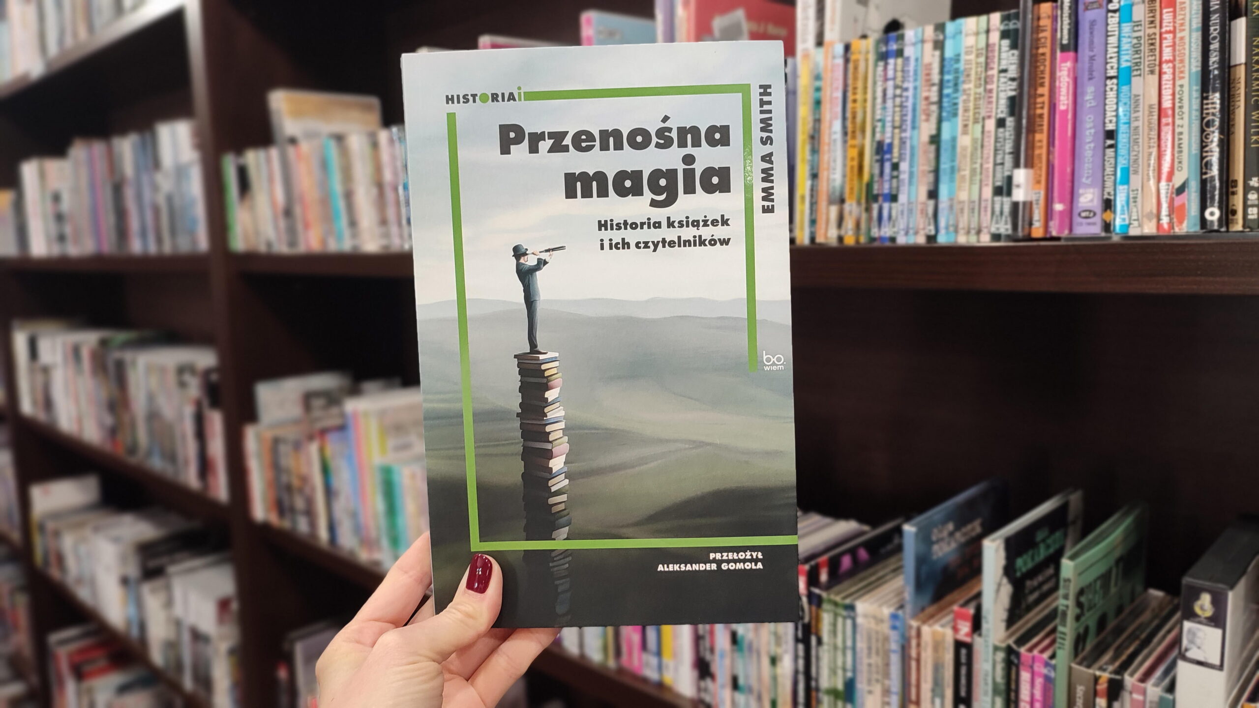 zdjęcie na tle regałów przedstawiające książkę Przenośna magia